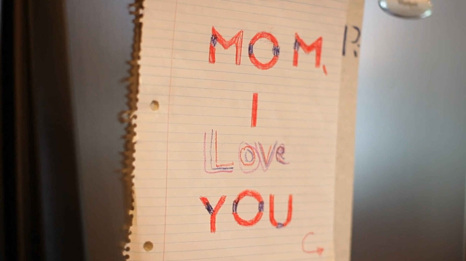 Sheet of paper with "Mom I love you" written in crayon.