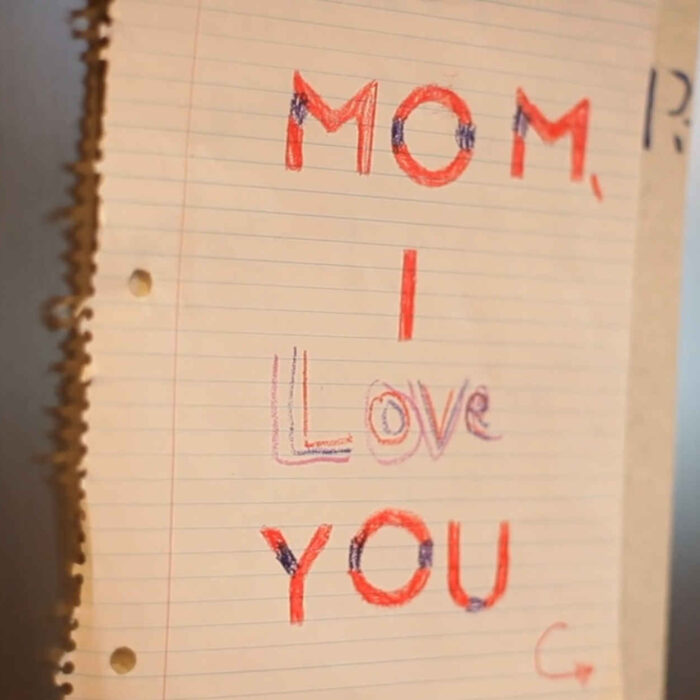 Sheet of paper with "Mom I love you" written in crayon.